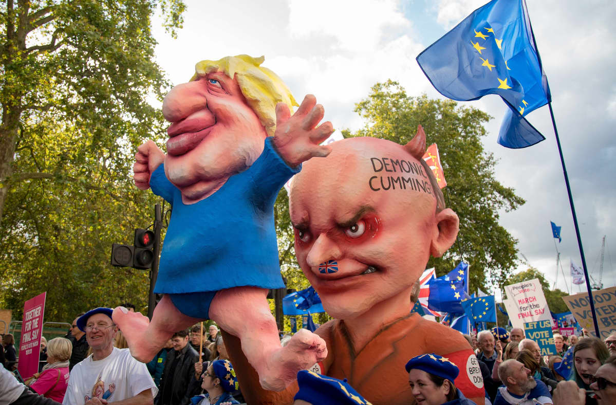 Mielenosoitukset kuljettavat kahta suurta hahmoa, jotka esittävät Britannian pääministeriä ja tämän neuvonantajaa. Cummings on esitetty natsimaisena hahmona, joka ohjailee Boris Johnsonia kuin nukkea.