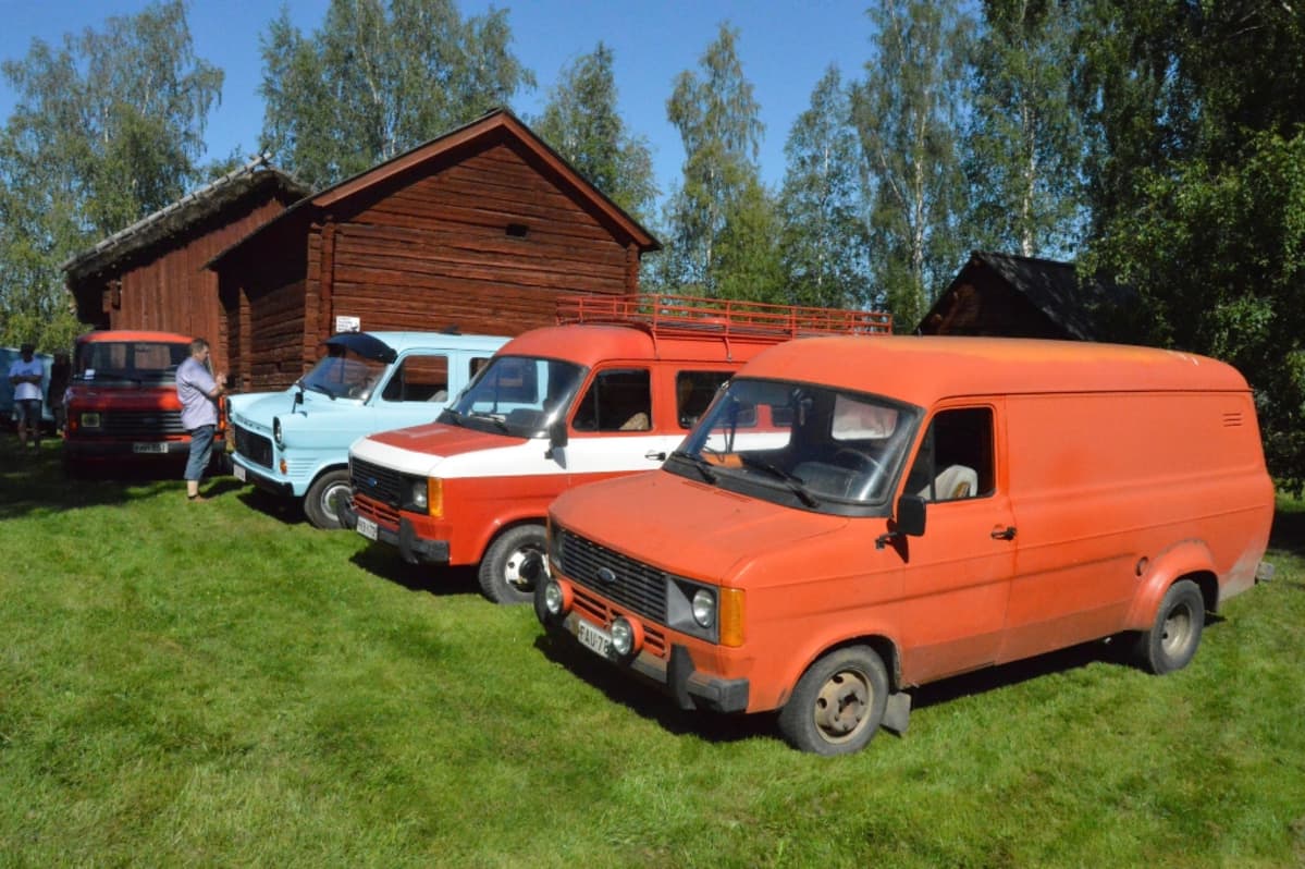erivärisiä pakettiautoja rivissä