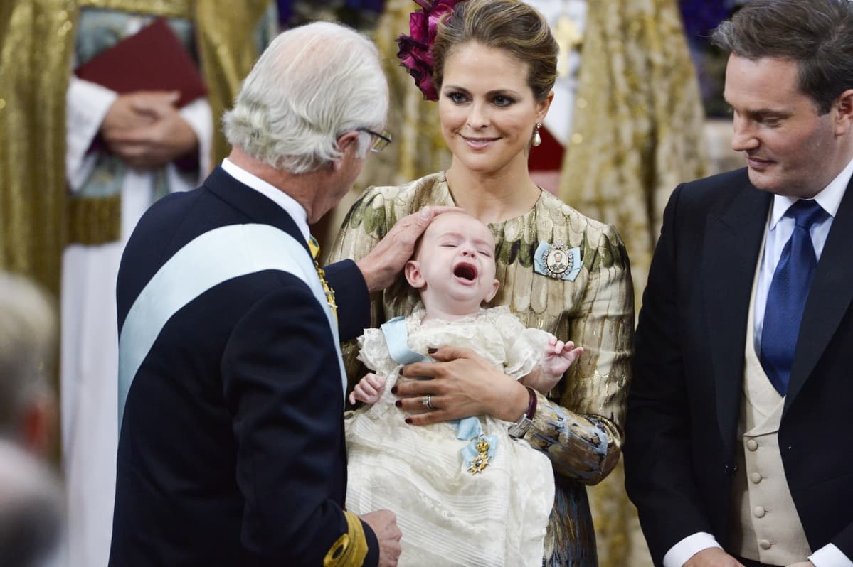 Kaarle Kustaa silittää kolmannen lapsenlapsensa prinssi Nicolasin päätä kastetilaisuudessa.