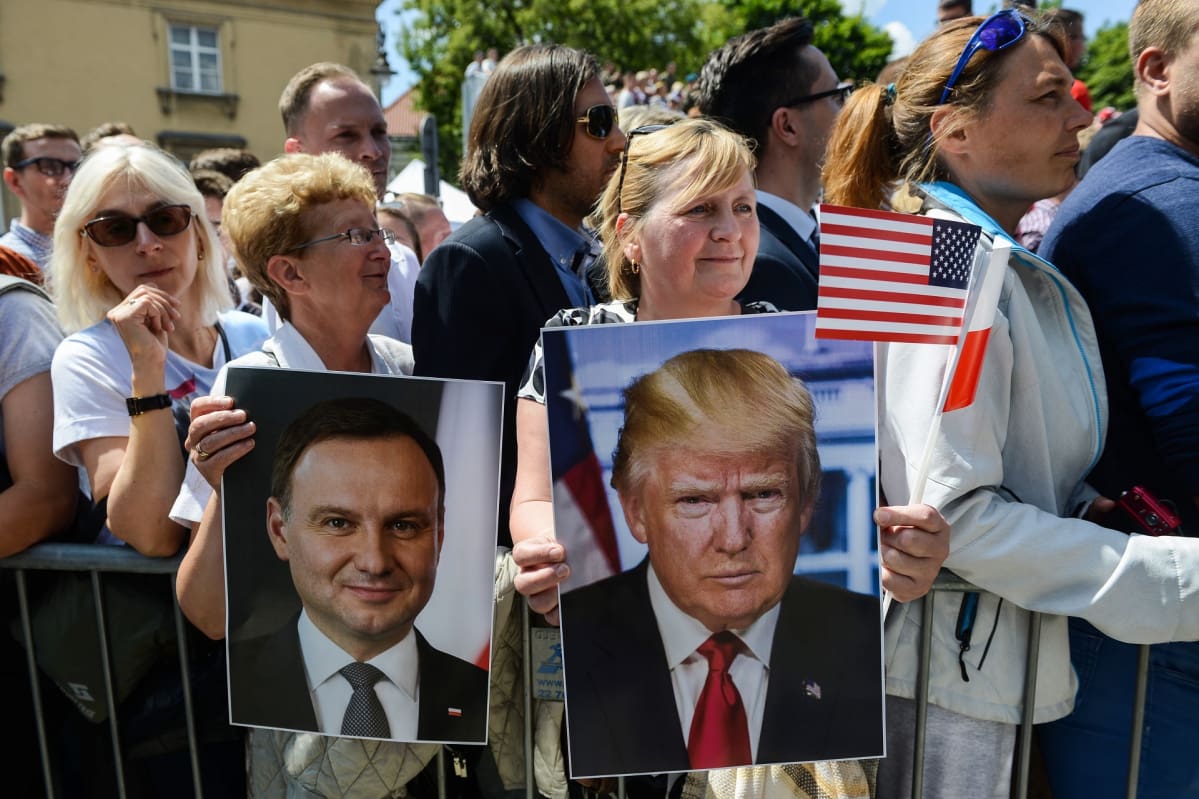 Puolalaisia käsissään Yhdysvaltain ja Puolan presidentin kuvia sekä maiden lippuja.