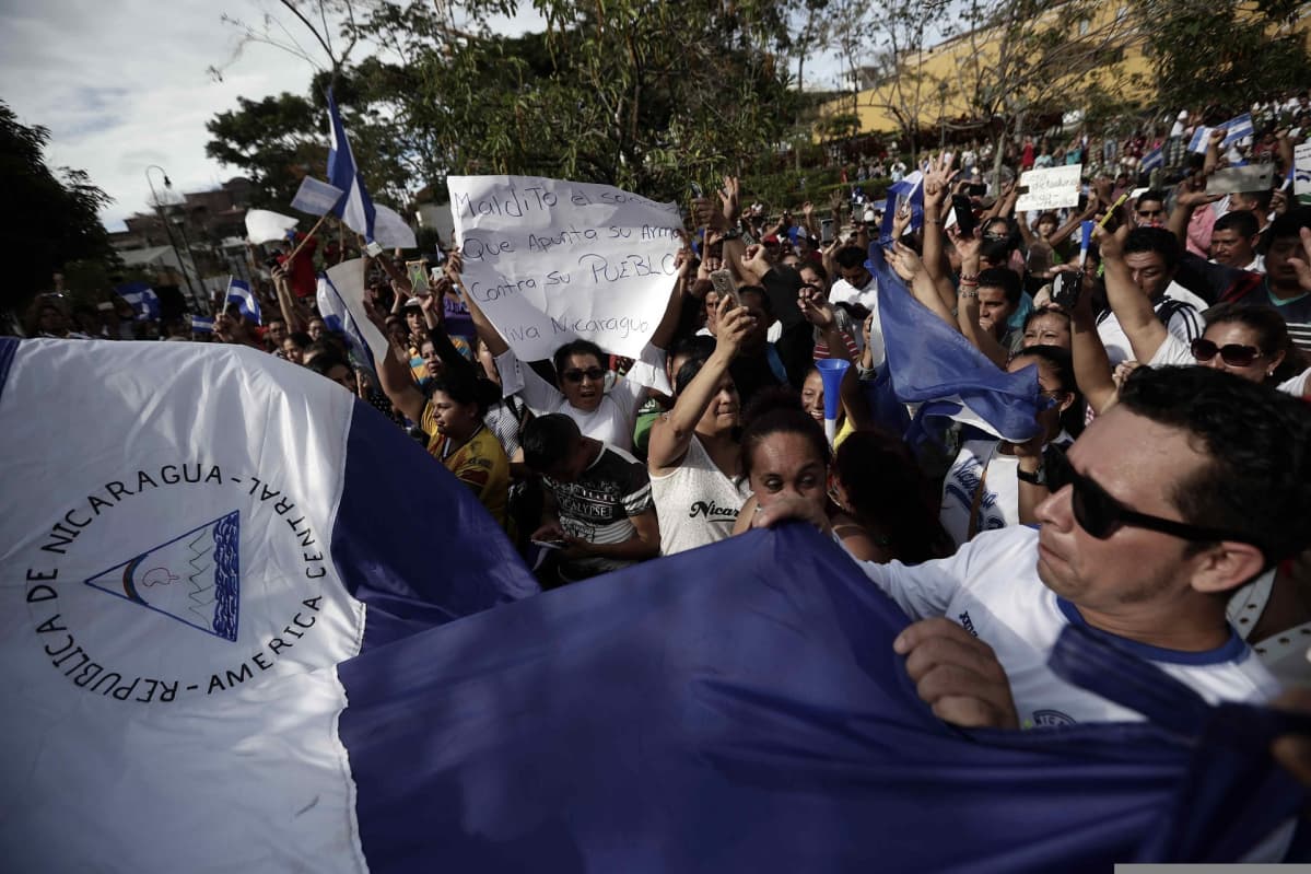 Mielenosoittajat heiluttavat lippuja ja kantavat kylttejä Nicaraguassa.