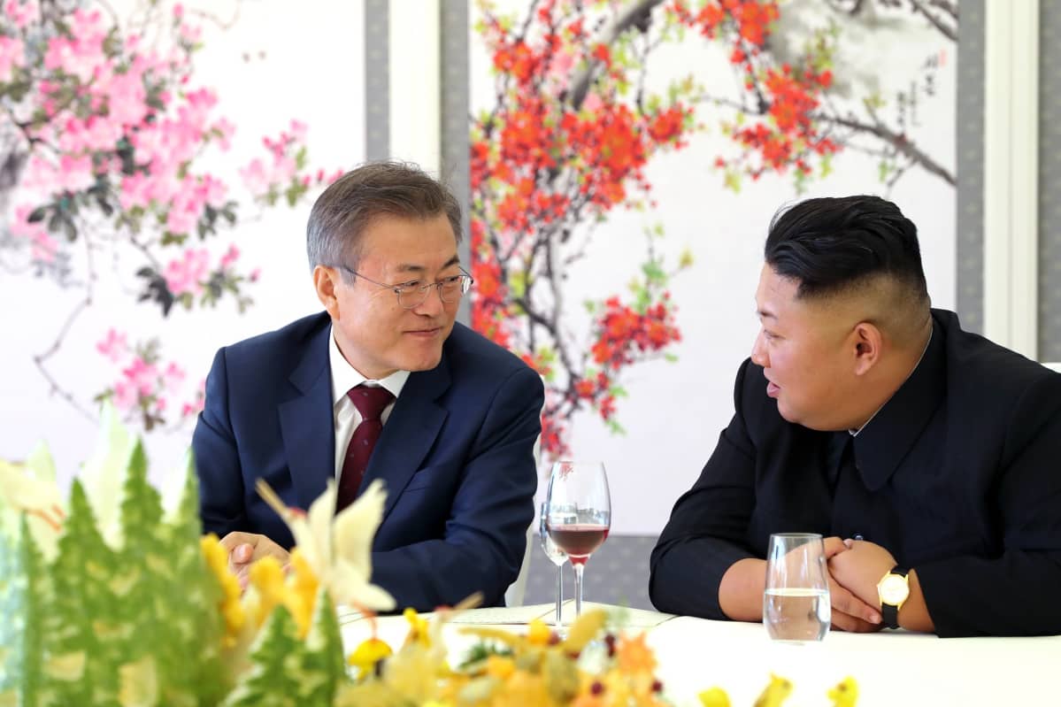 Etelä-Korean presidentti Moon Jae-in ja Pohjois-Korean johtaja Kim Jong-un keskustelevat. Molemmat hymyilevät.