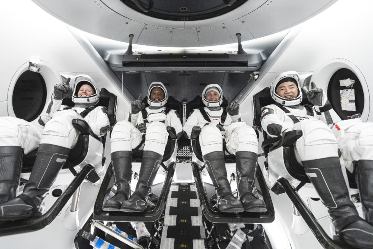 Neljä astronauttia avaruuspuvuissa istumassa aluksessaan.