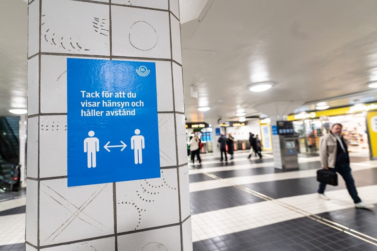 Metroaseman pylvääseen on liimattu kyltti, jossa lukee: Tack för att du visar hänsyn och håller avstånd