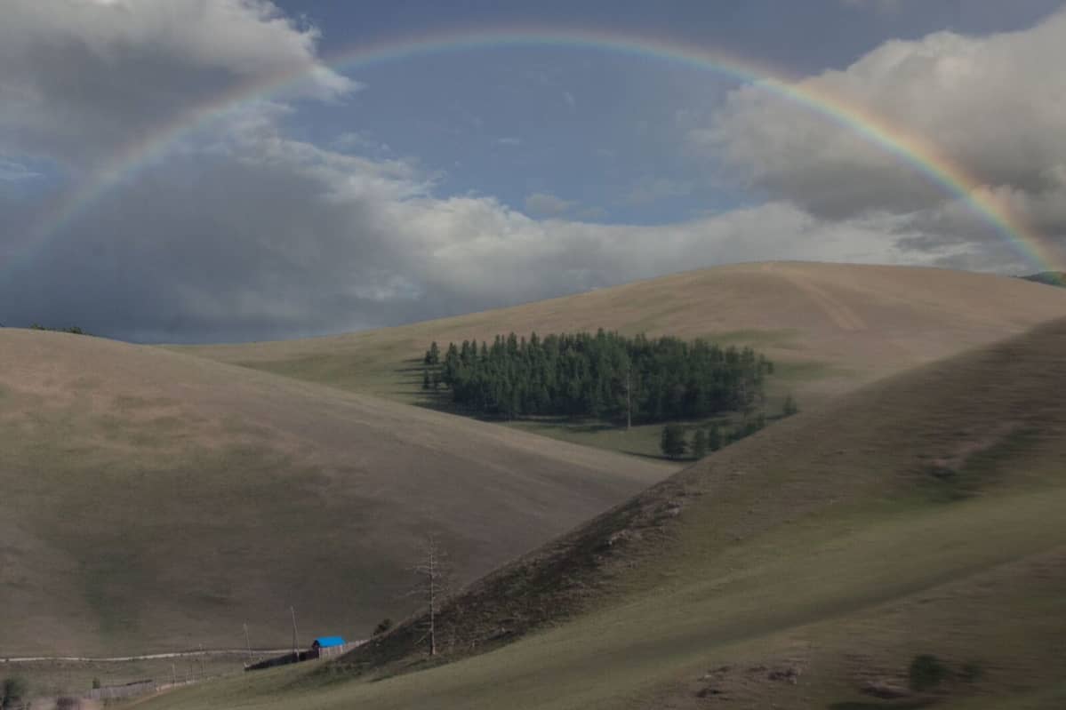 Sininen talo Mongolian aavikolla ja taivaalla sateenkaari