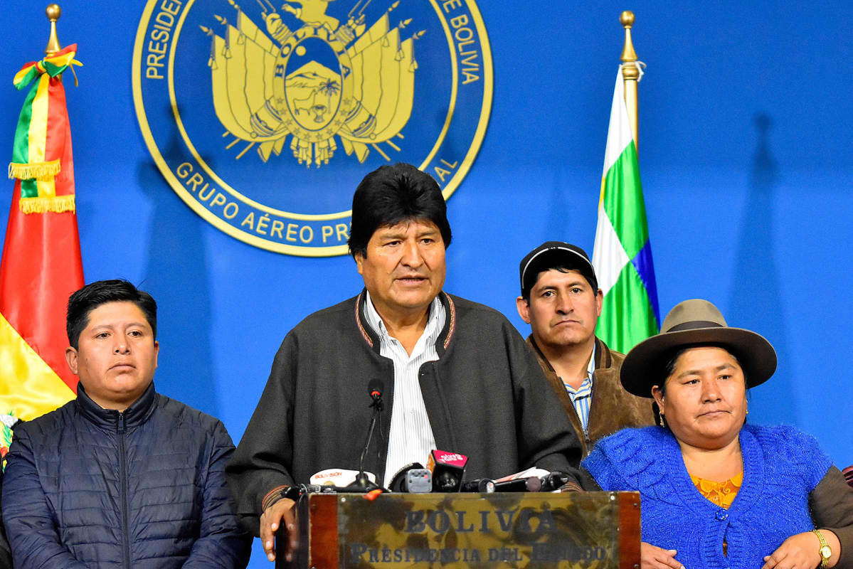 Evo Morales puhuu korokkeen takana. Vieressä seisoo hänen kannattajiaan.