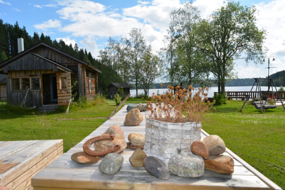 Kantturan pihan vanhalla pöydällä on kauniisti aseteltuna tuohikori, jossa on kukkia, kiviä ja ruosteisia hevosenkenkiä.