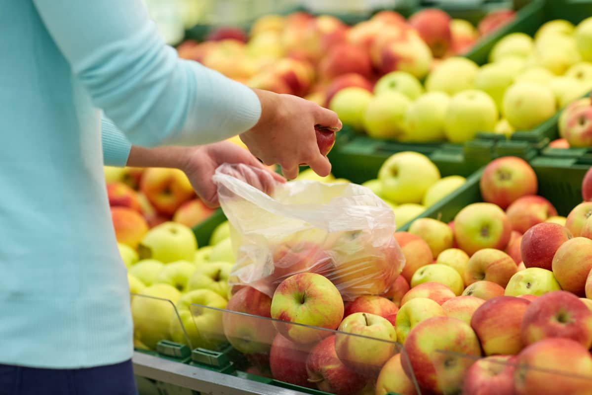 Person plockar frukter i plastpåse