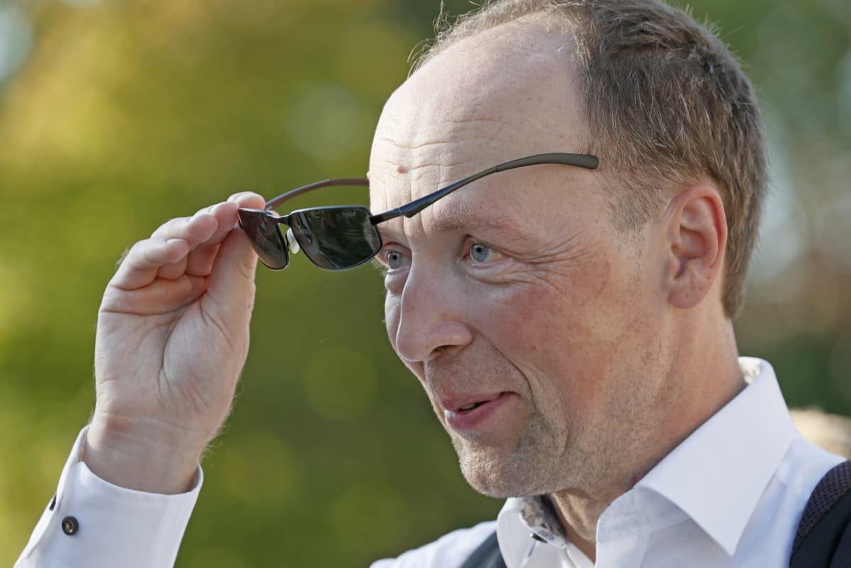 Porträttbild på Jussi Halla-aho när han tar på sig ett par svarta solglasögon.