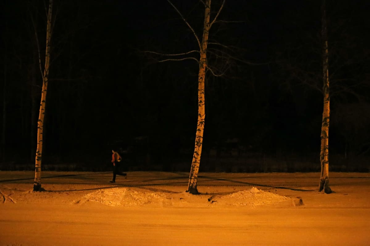 Nainen juoksee lumisella tiellä.