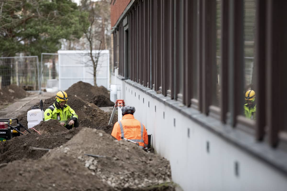 Miehet asentavat ilmastointiputkia maanalle
