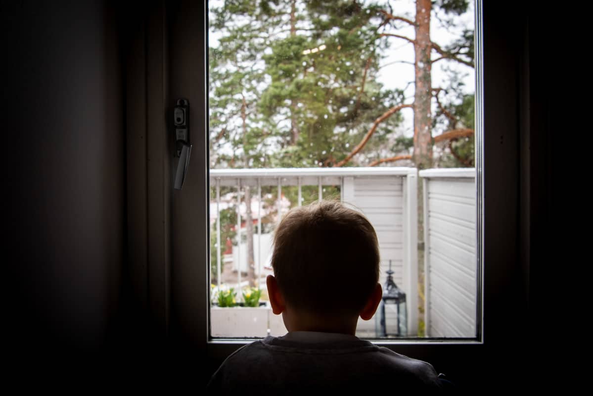 Lapsi katsoo ikkunasta ulos.