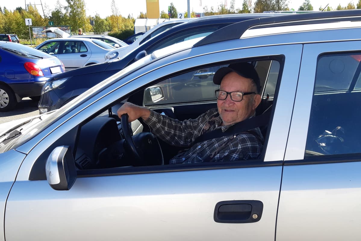 Seppo Kortelainen istuu autossaan ja katsoo kameraan.
