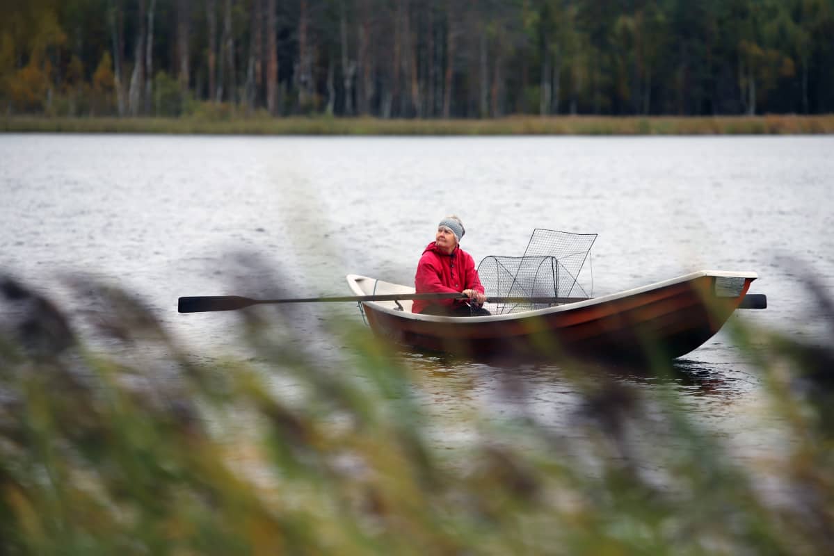nainen soutaa lammella.