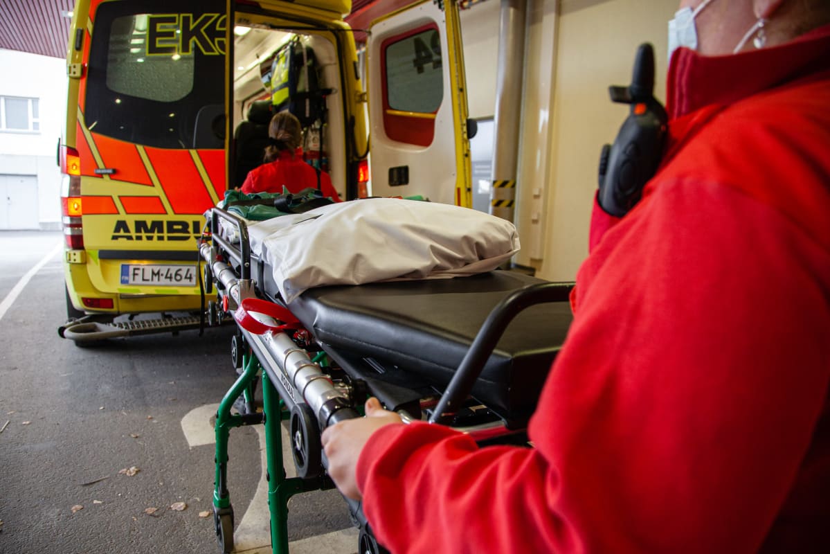 Ensihoitajat lastaamassa tyhjiä paareja ambulanssiin.
