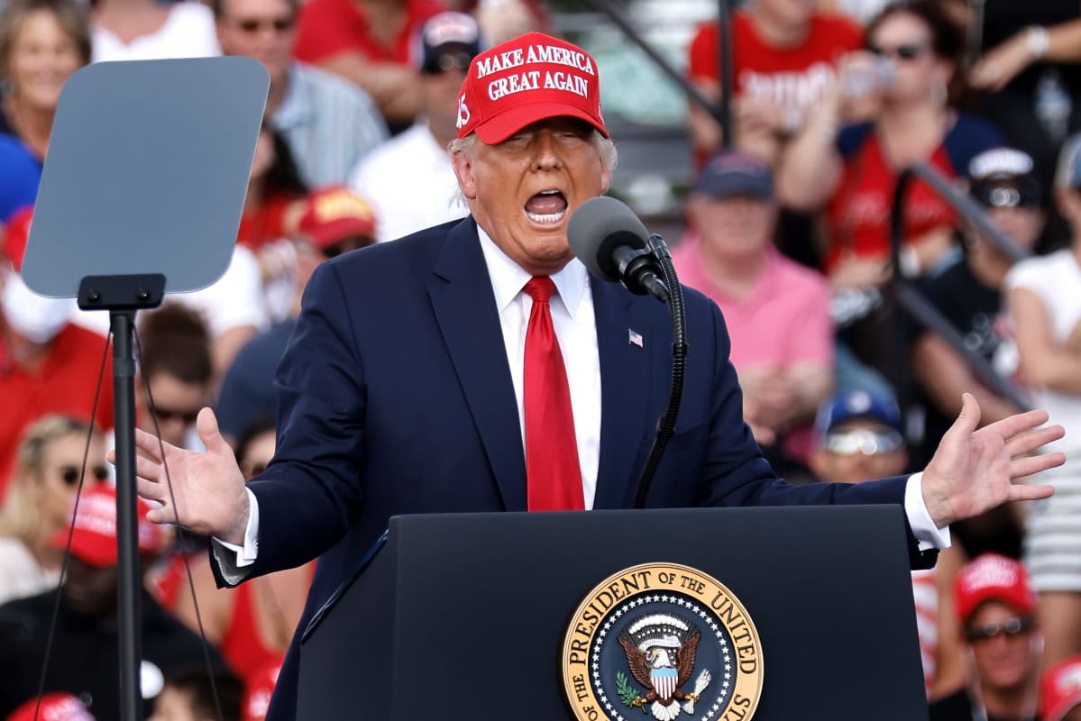 Trump punaisessa lippalakissa puhuu kannattajilleen.
