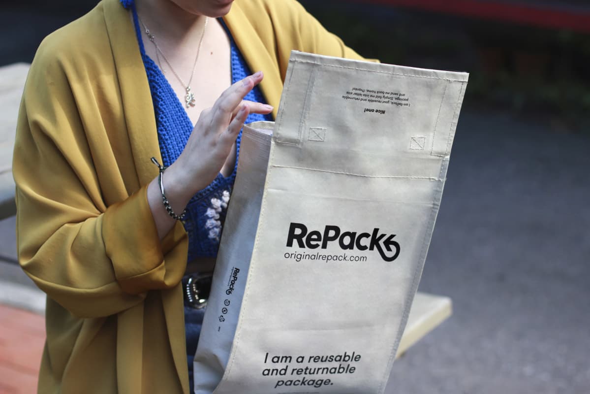 Naisella on kädessä RePack-kestopakkaus.