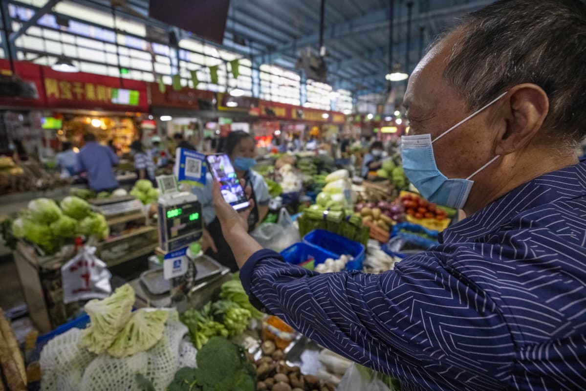 Kiinan Hangzhoussa tuoretuotteita myyvällä torilla asiakas skannasi QR-maksukoodia ostosten tekemistä varten 27. syyskuuta 2020.