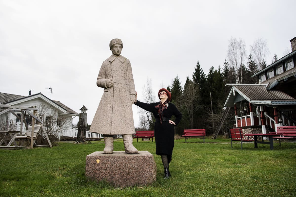 Aira Samulin poseeraa isänsa patsaan kanssa marraskuussa 2020.