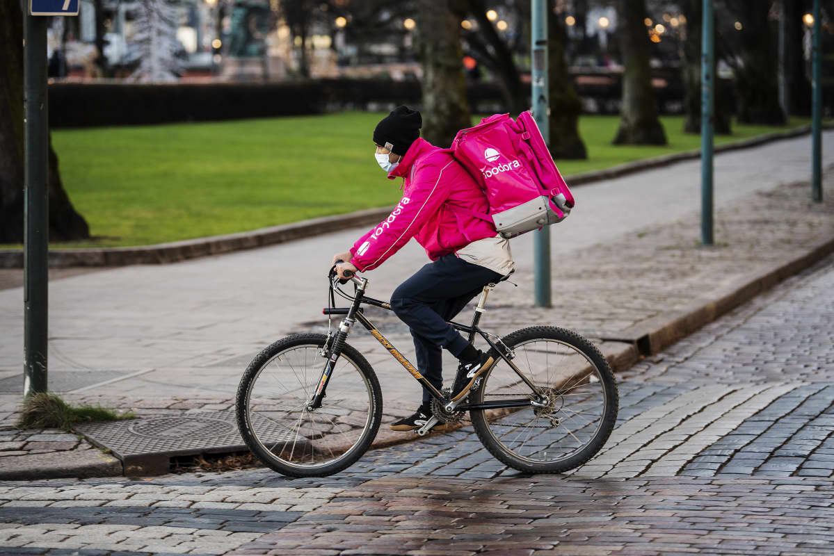 Foodoran ruokalähetti polki Helsingin keskustassa kasvomaski kasvoillaan joulukuussa 2020.