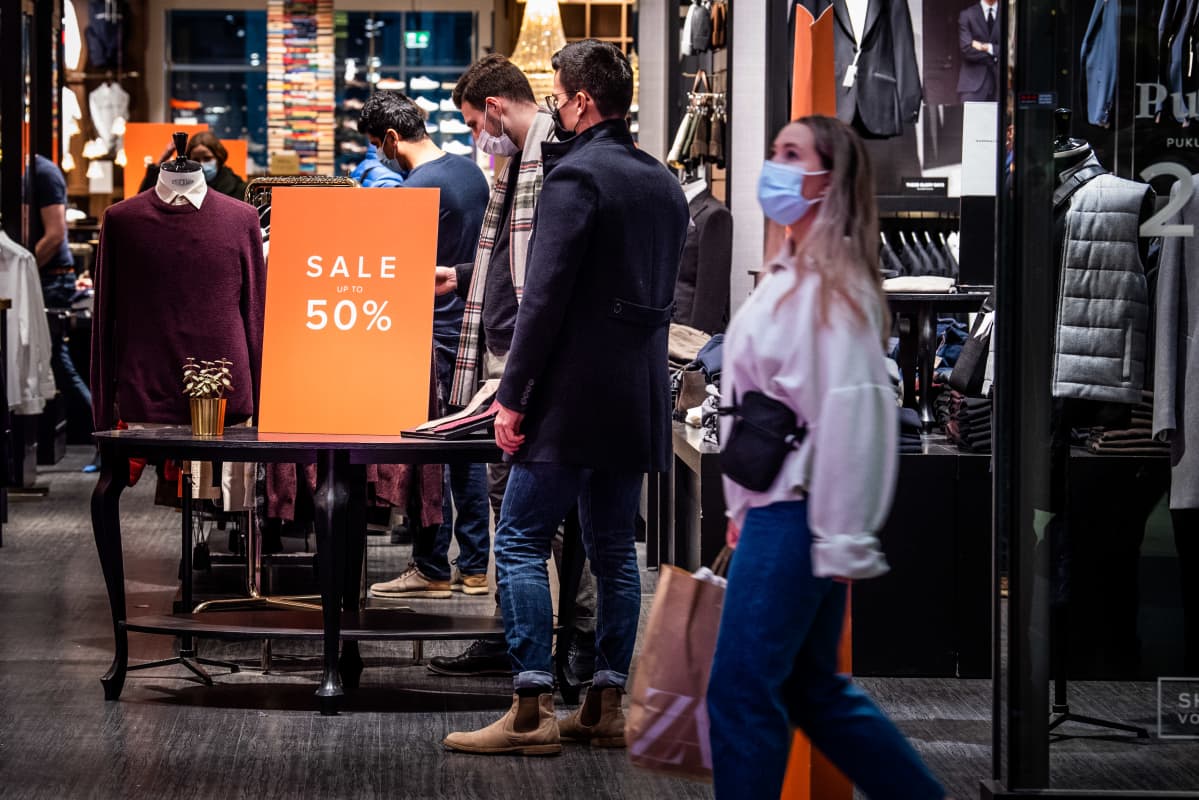 Miehet katselevat vaatekaupassa alennuksessa olevia tuotteita.