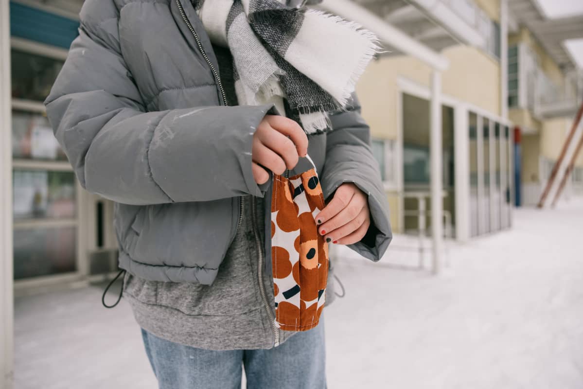 Oppilas kasvomaski kädessä välitunnilla.