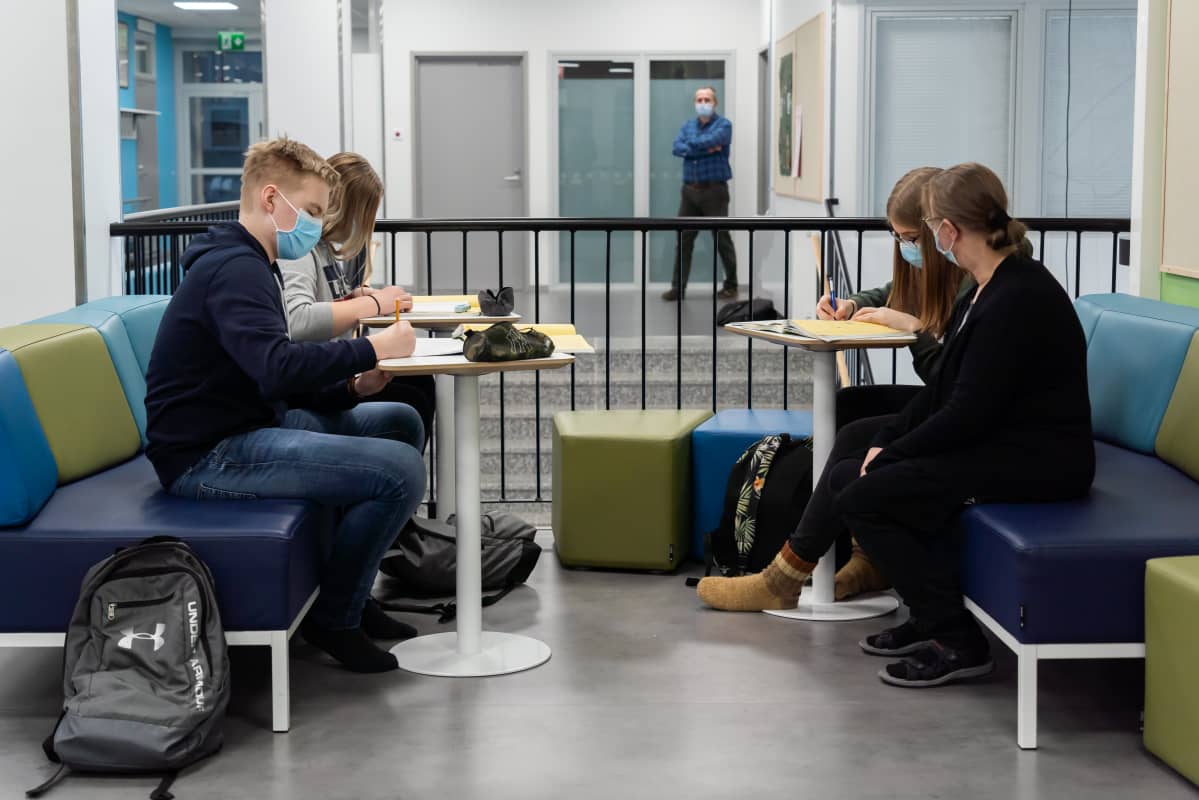 Opinto-ohjaaja Sari Heinonen seuraa, kun 9.-luokkalaiset Siiri Ylösmäki, Vilma Rautava ja Topias Kaapu tekevät matematiikan tehtäviä.