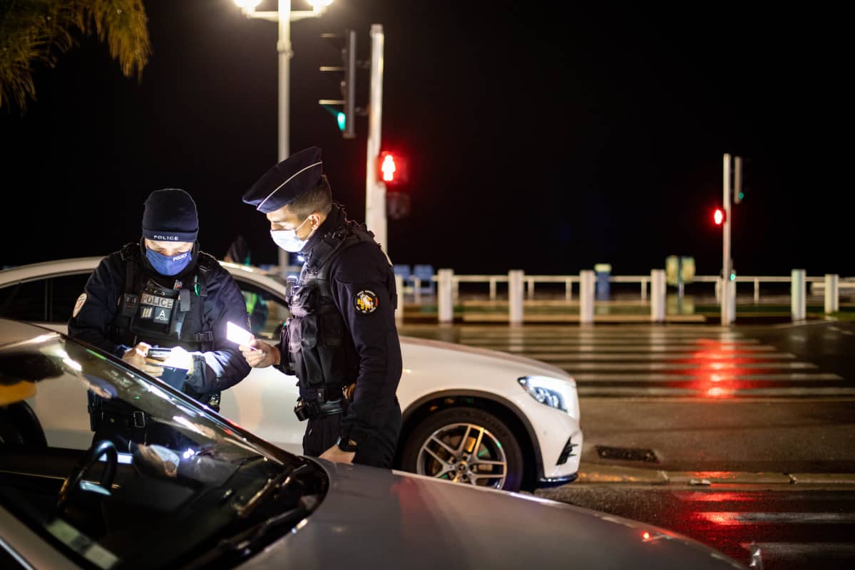 Poliisit tarkistavat autoilijan papereita pimeällä.