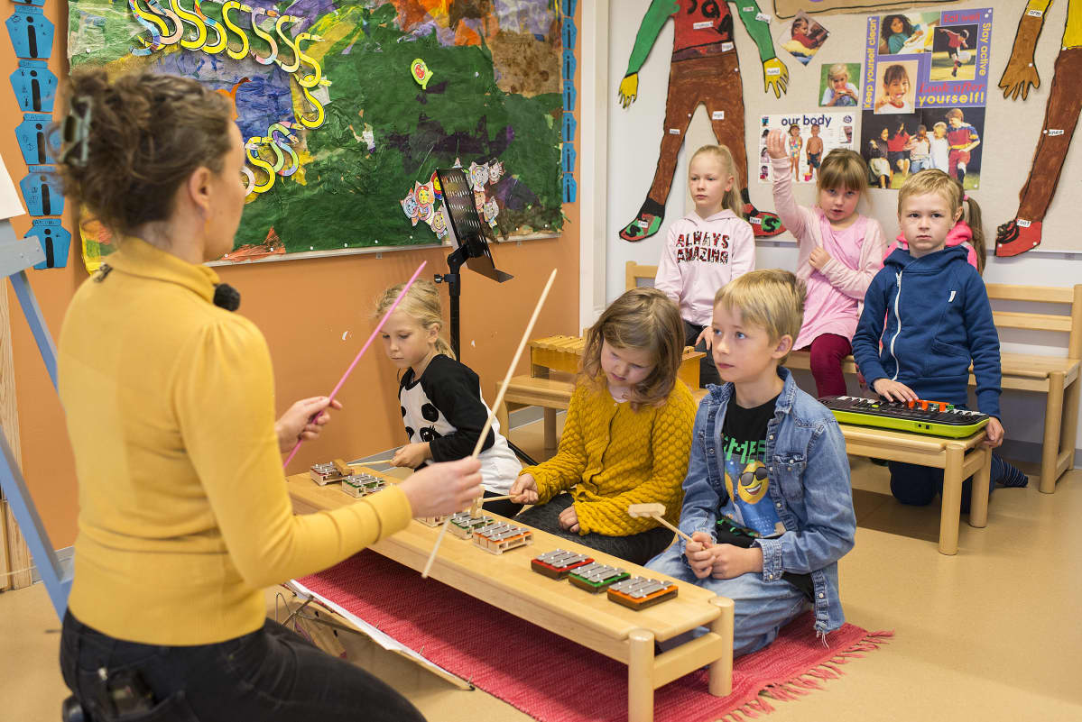 Opettaja ja oppilaat musiikintunnilla.