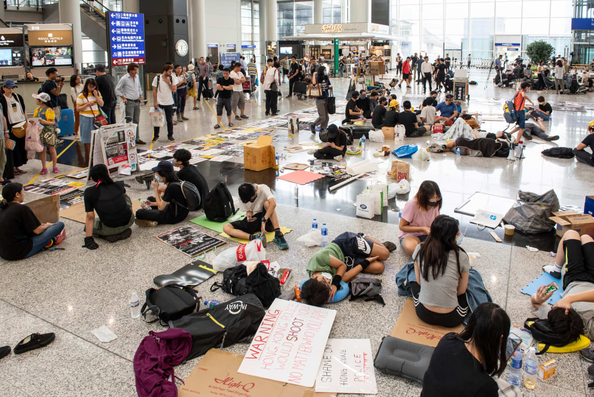Kuvassa mielenosoittajat ovat vallanneet Hong Kongin kansainvälisen lentokentän aulan istumalla alueella tavarat levitettyinä.