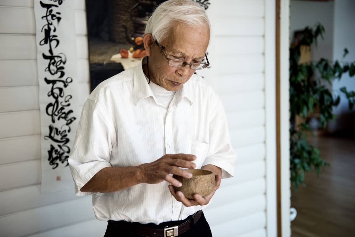Tran Minh Canh silittää käsissään kookospähkinän puolikasta. Sileäksi hiottu kulho oli lautanen saarella, jonne perhe haaksirikkoutui 40 vuotta sitten, ennen saapumista Suomeen.