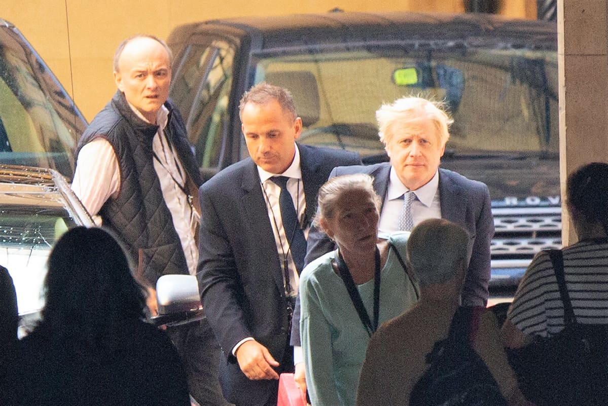 Dominic Cummings ja Boris Johnson saapuvat parlamenttiin pääministerin kyselytunnille. Johnsonilla on tumma puku, Cummingsilla liivit ja valkoinen paita.