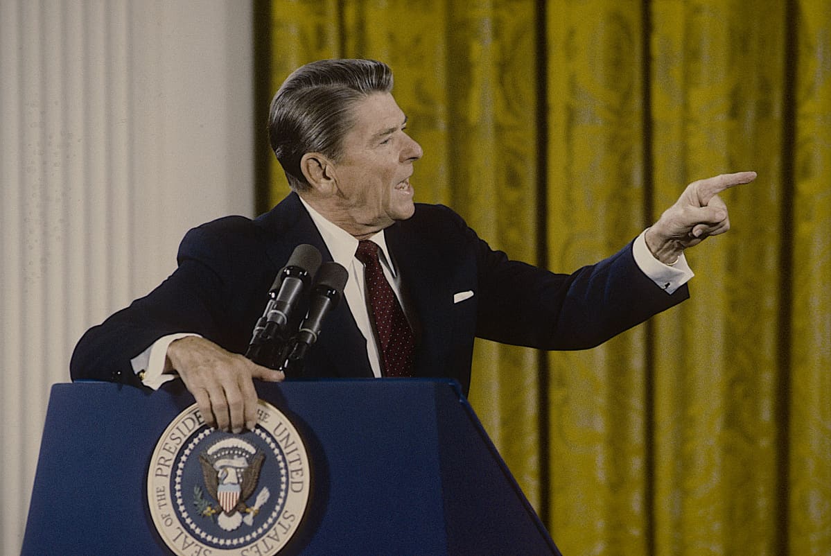 Presidentti Ronald Reagan puhujapöntössä viittoilee voimakkaasti.