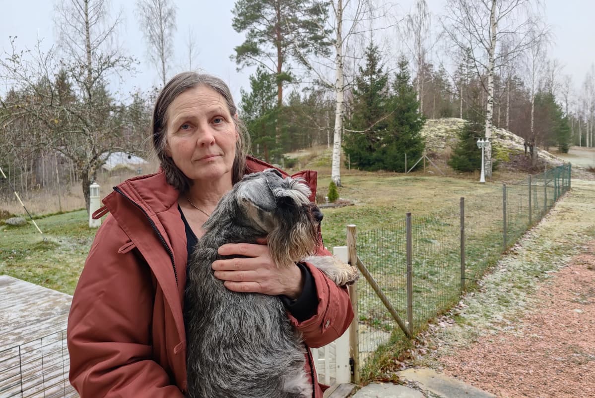 Annamari Warjus koira sylisään pihallaan Puumalassa.