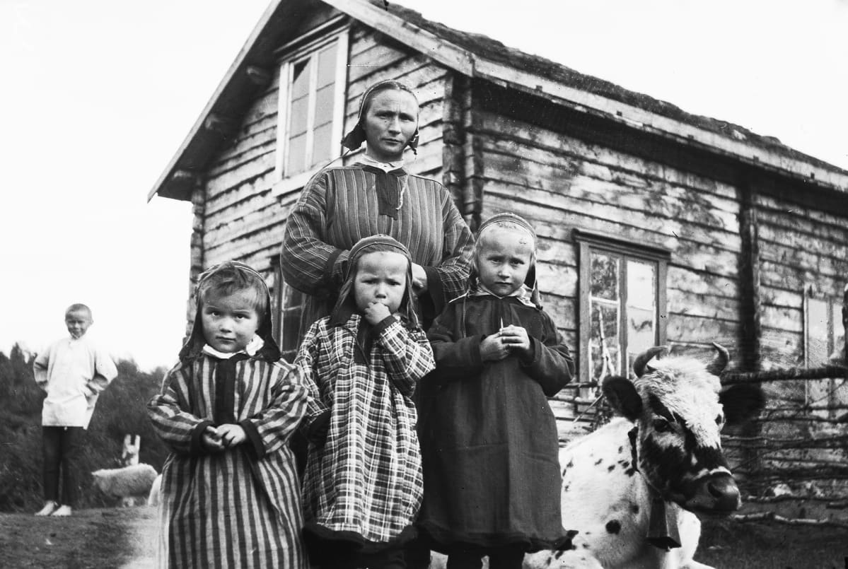 Inarilaisia pikkutyttöja ja heidän äitinsä kodin pihalla.