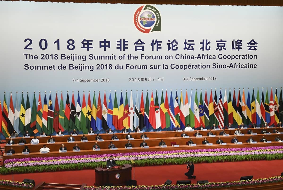Kuvassa puhujanpöntössä Kiinan presidentti Xi Jinping. Hänen takanaan Afrikan maiden johtajia. Taustalla Afrikan maiden lippuja ja keskellä Kiinan lippu.
