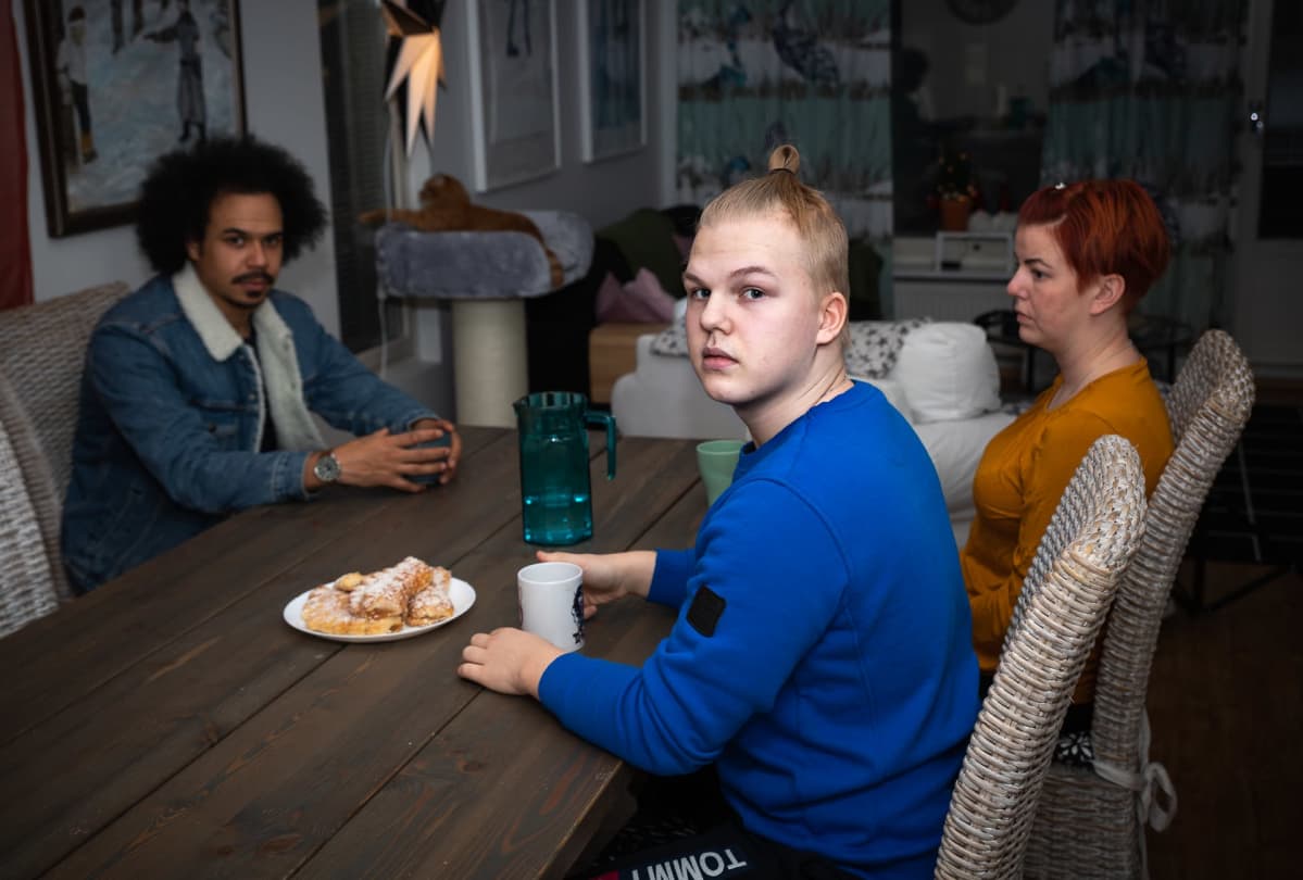 Jasper ja Tiina Mäki-Jokela istuvat kahvipöydän ääressä Perjantain juontajan Sean Ricksin kanssa.
