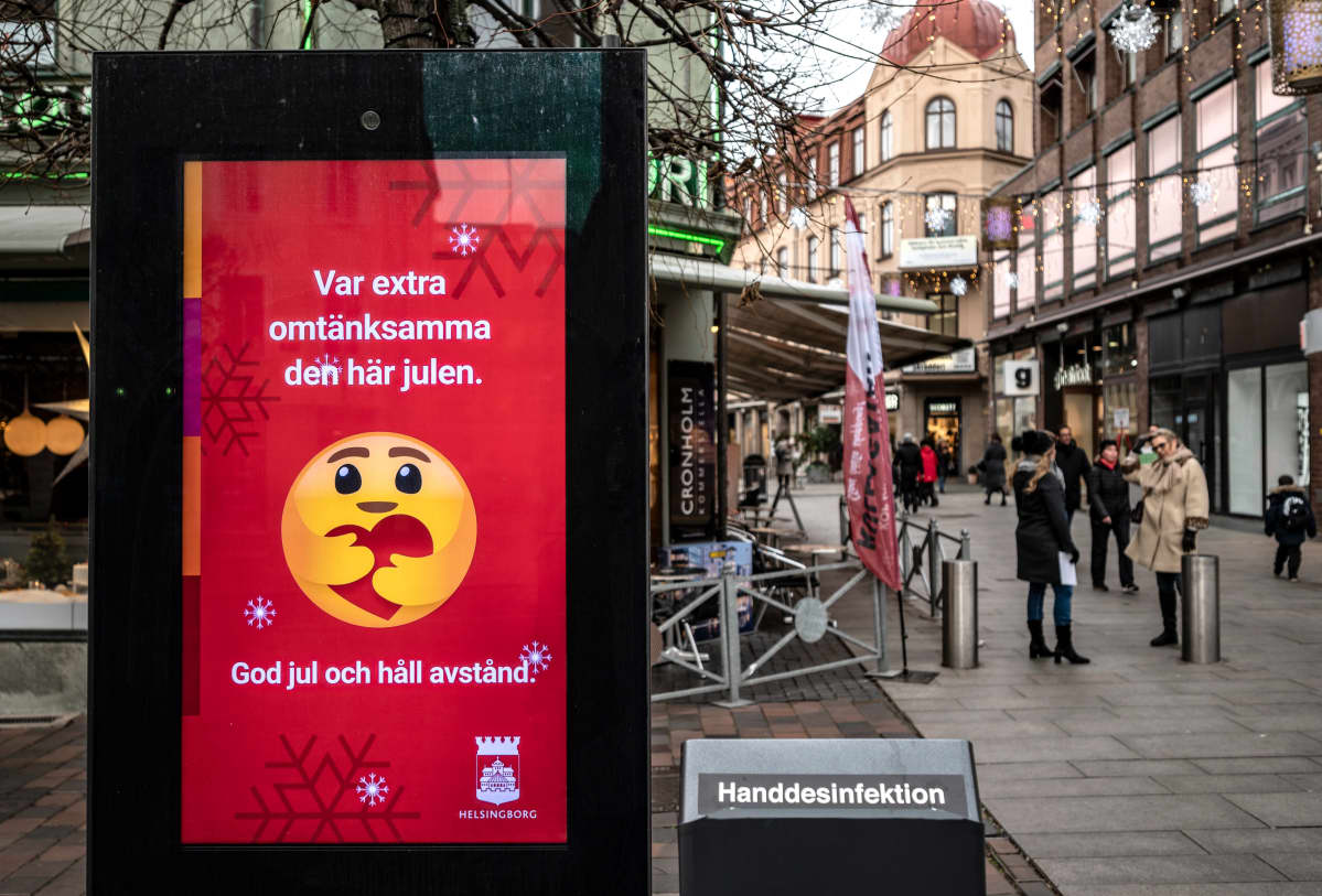 Kävelykadulla oleva kyltti. Taustalla ihmisiä.