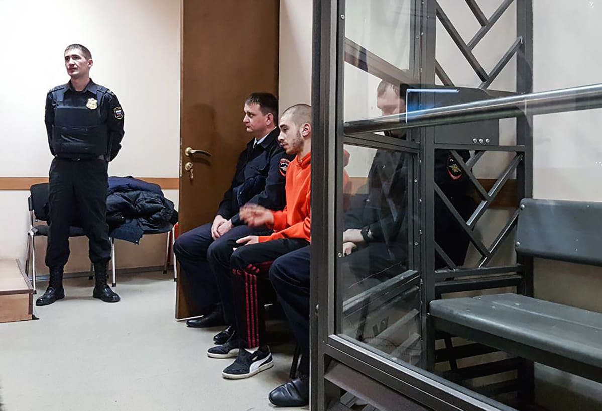 Venäläinen rap-artisti Husky odottaa poliisien kanssa pääsyä oikeussaliin.