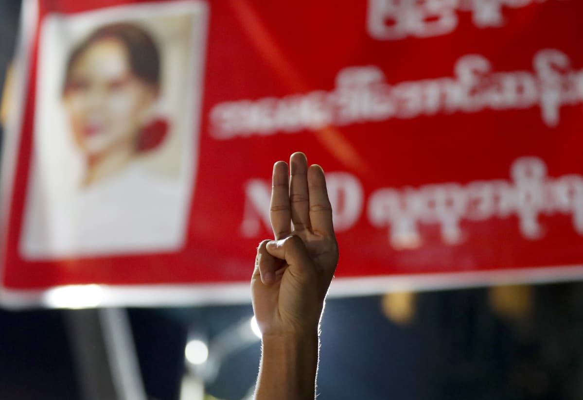 Yangonissa mielenosoittaja kohotti kolme sormea armeijan syrjäyttämän Aung San Suu Kyin kuvalle. Kyseessä on vastarinnan symboli.
