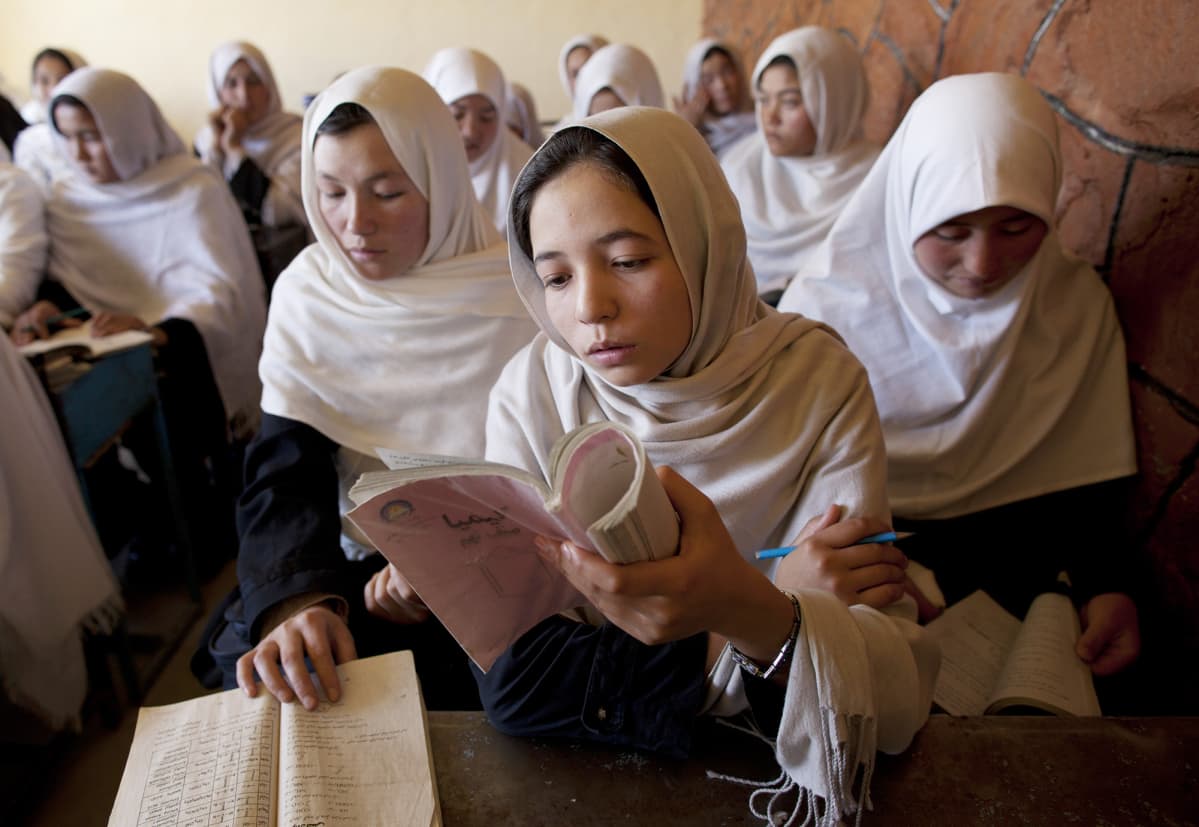 Afghanistanilaiset tytöt lukevat kirjaa koulussa.