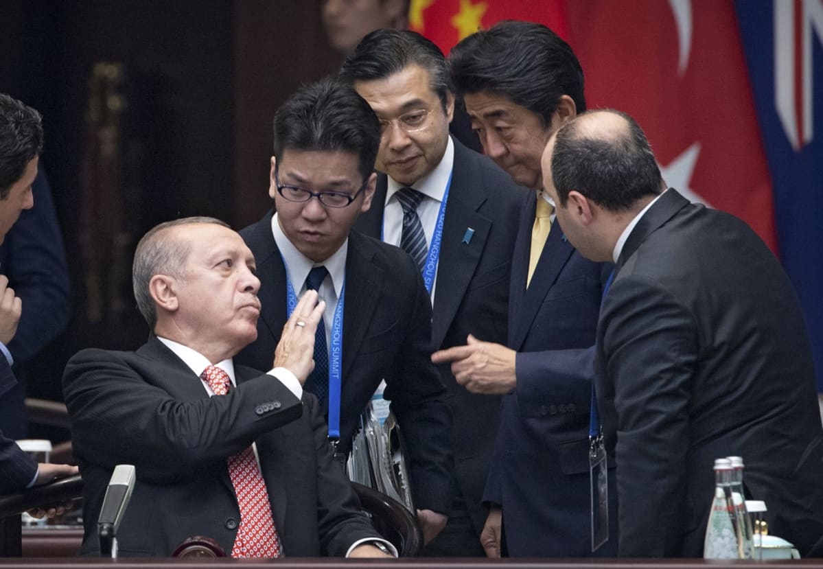 Erdoğan istuu, miehet ympärillä seisovat.
