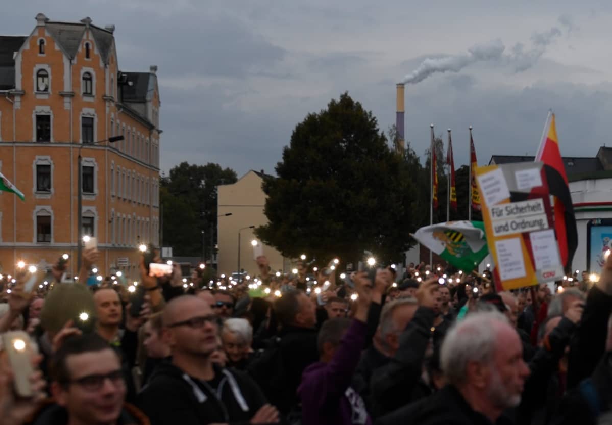 Joukko mielenosoittajia. Kännykät loistavat kuin kynttilät pimenevässä illassa.