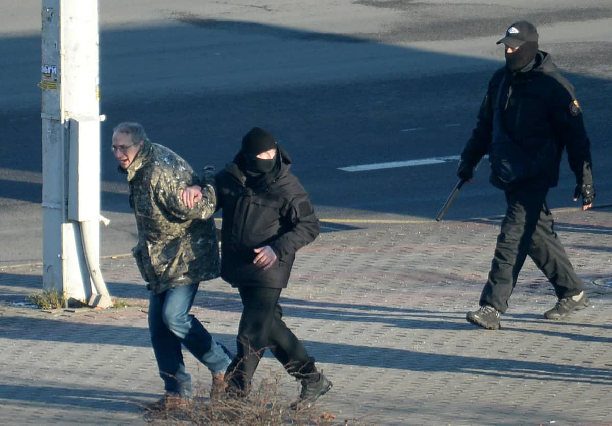 Poliisi ottaa kiinni mielenosoittajaa.