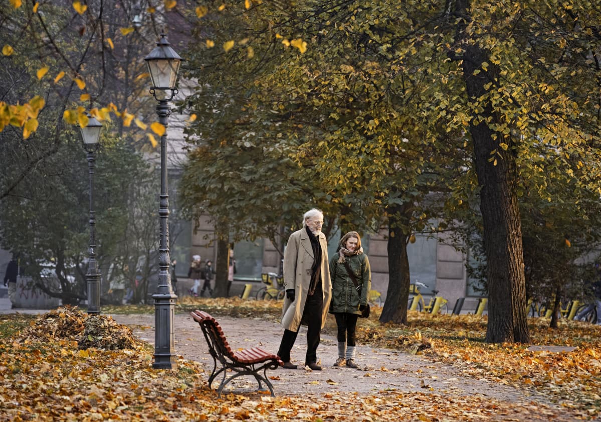 Olavi (Heikki Nousiainen) och Lea (Pirjo Lonka) promenerar tillsammans i en höstlig park.