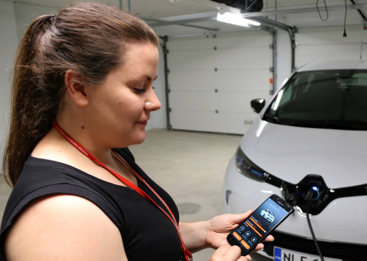 Penttilänrannan monisukupolvikorttelin yhteisökoordinaattori Minna Patama näyttää, kuinka yhteiskäytössä oleva sähköauto varataan puhelinsovelluksella.