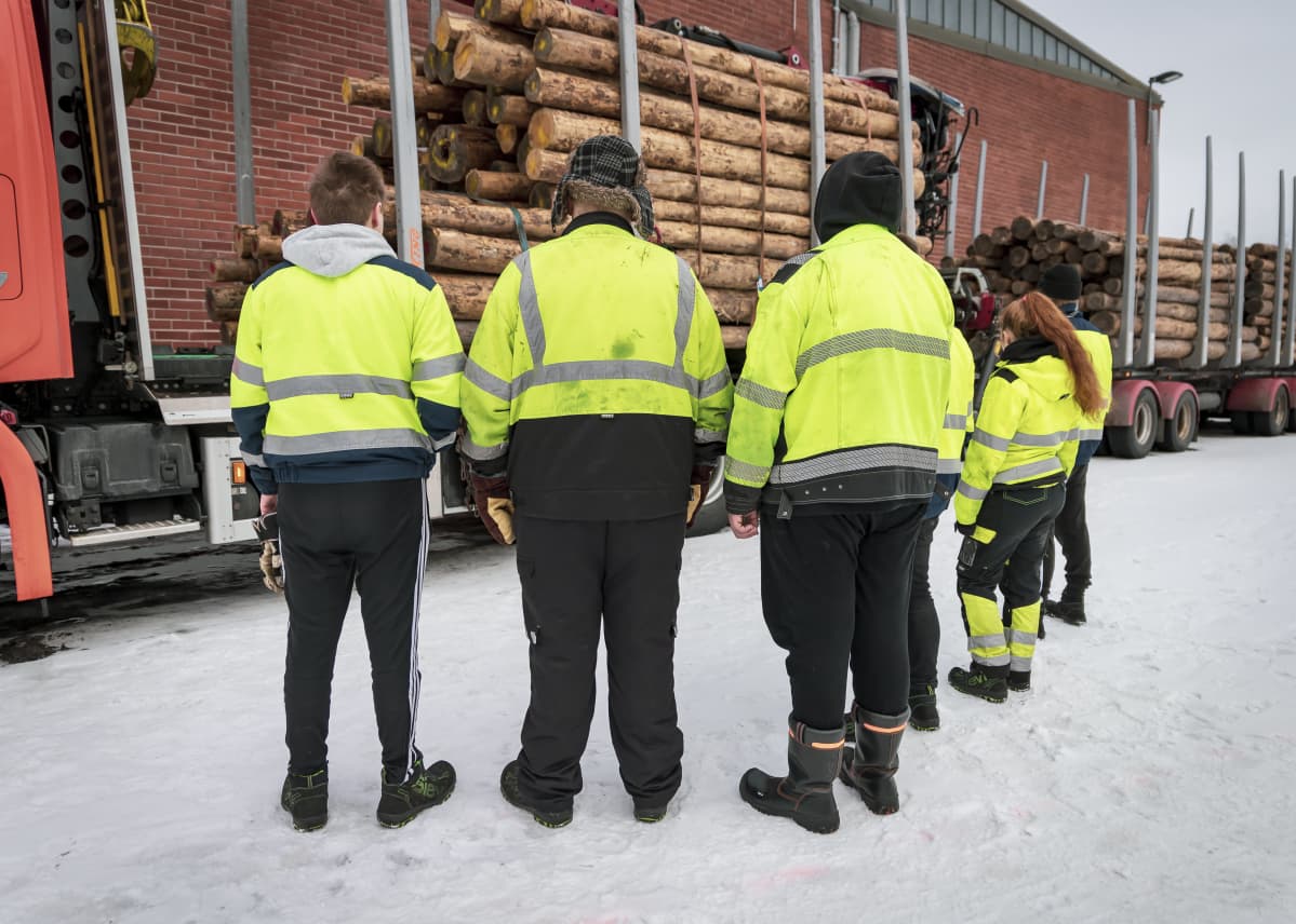 Ryhmä oppilaita katselee tukkirekkaa koulun pihassa.
