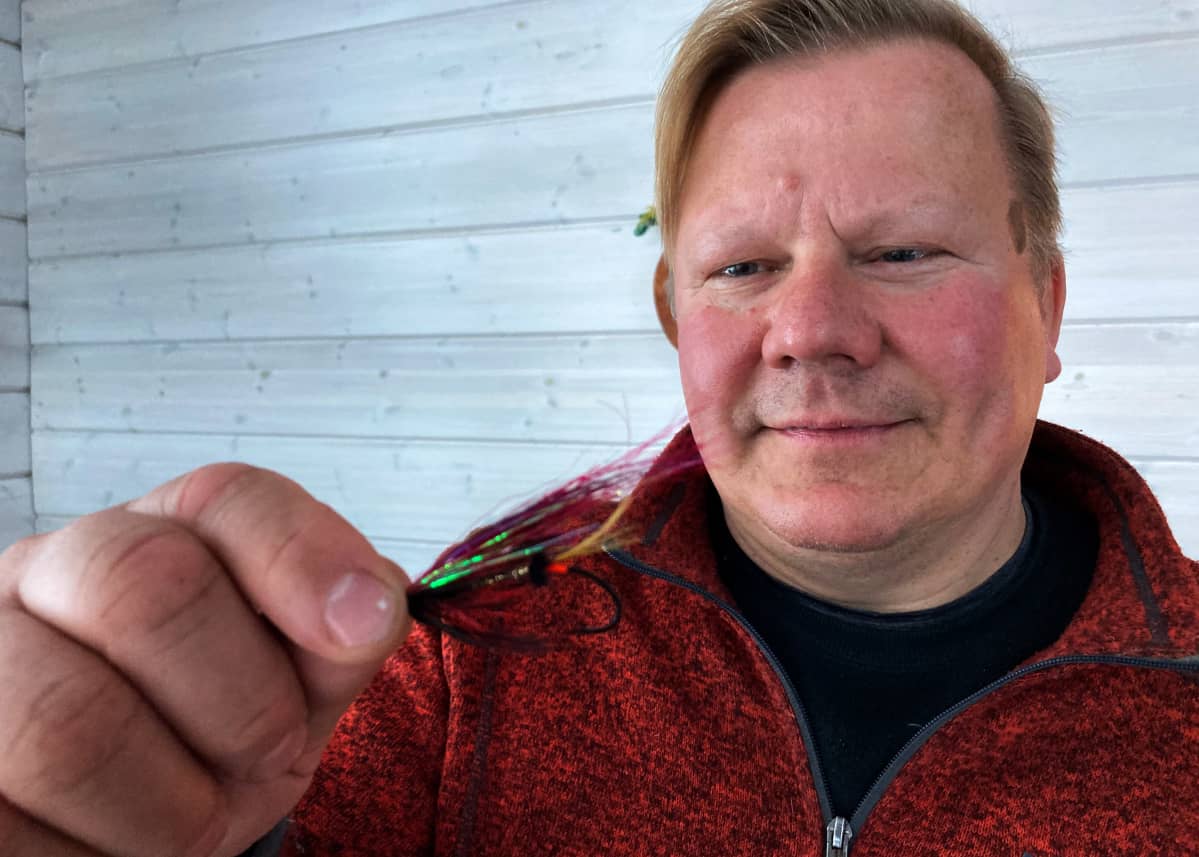 Punatakkinen mies pitää kädessään lohiperhoa.