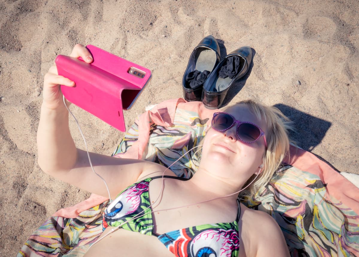 Jenni Hänninen katselee videota rannalla.