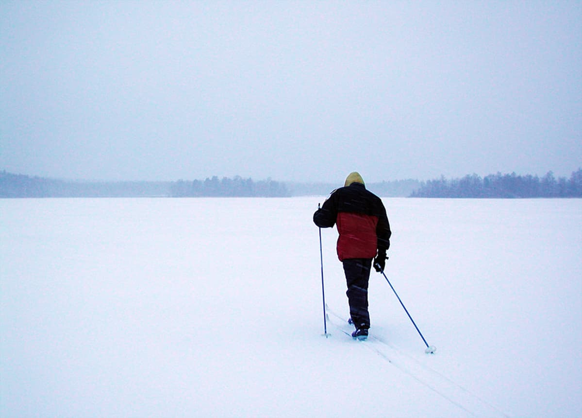 Mies hiihtämässä järvenjäällä.